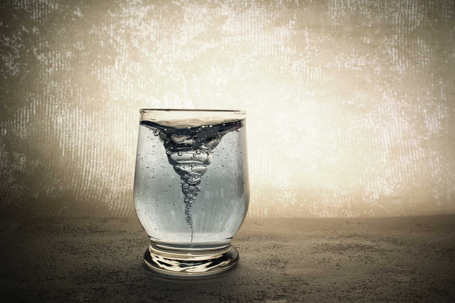 Wasserglas, in dem ein Wasserstrudel dargestellt ist, versinnbildlicht die Tiefe und die Entstehung von seelischen Symptomen